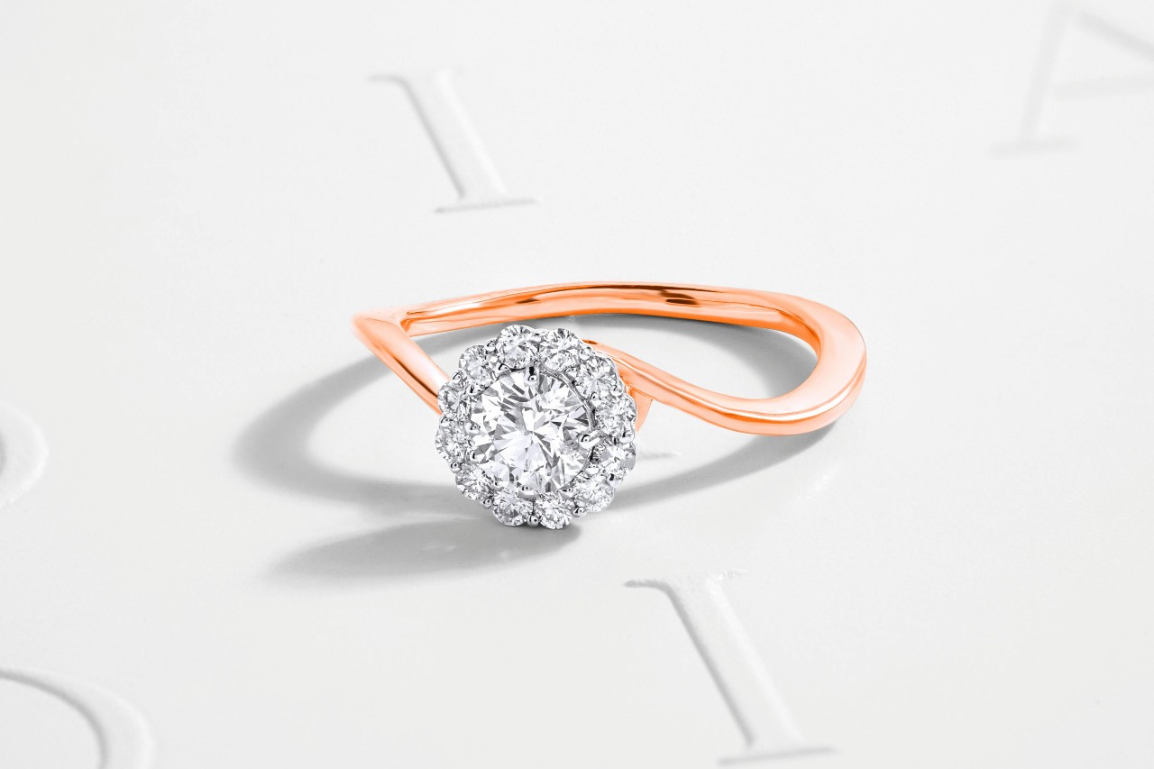 A halo engagement ring with a unique rose gold band.