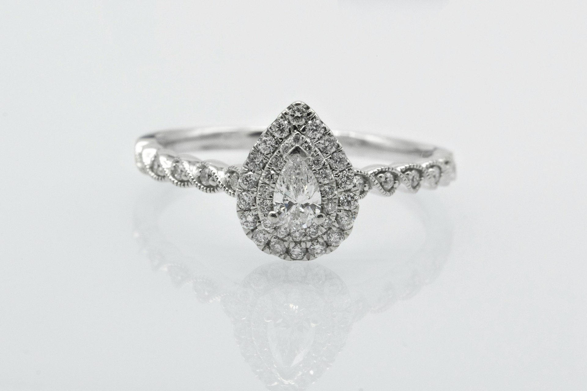 A double halo engagement ring with a pear shape diamond and unique band.