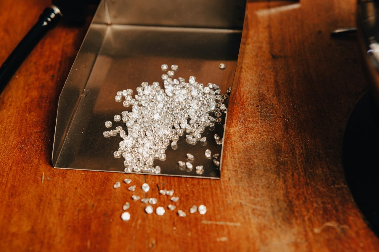 A handful of sparkling diamonds on a wooden counter.