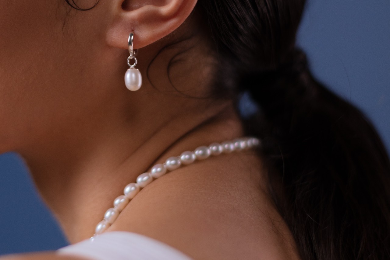 close up image of a woman wearing a pearl of pearl earrings and a matching pearl necklace
