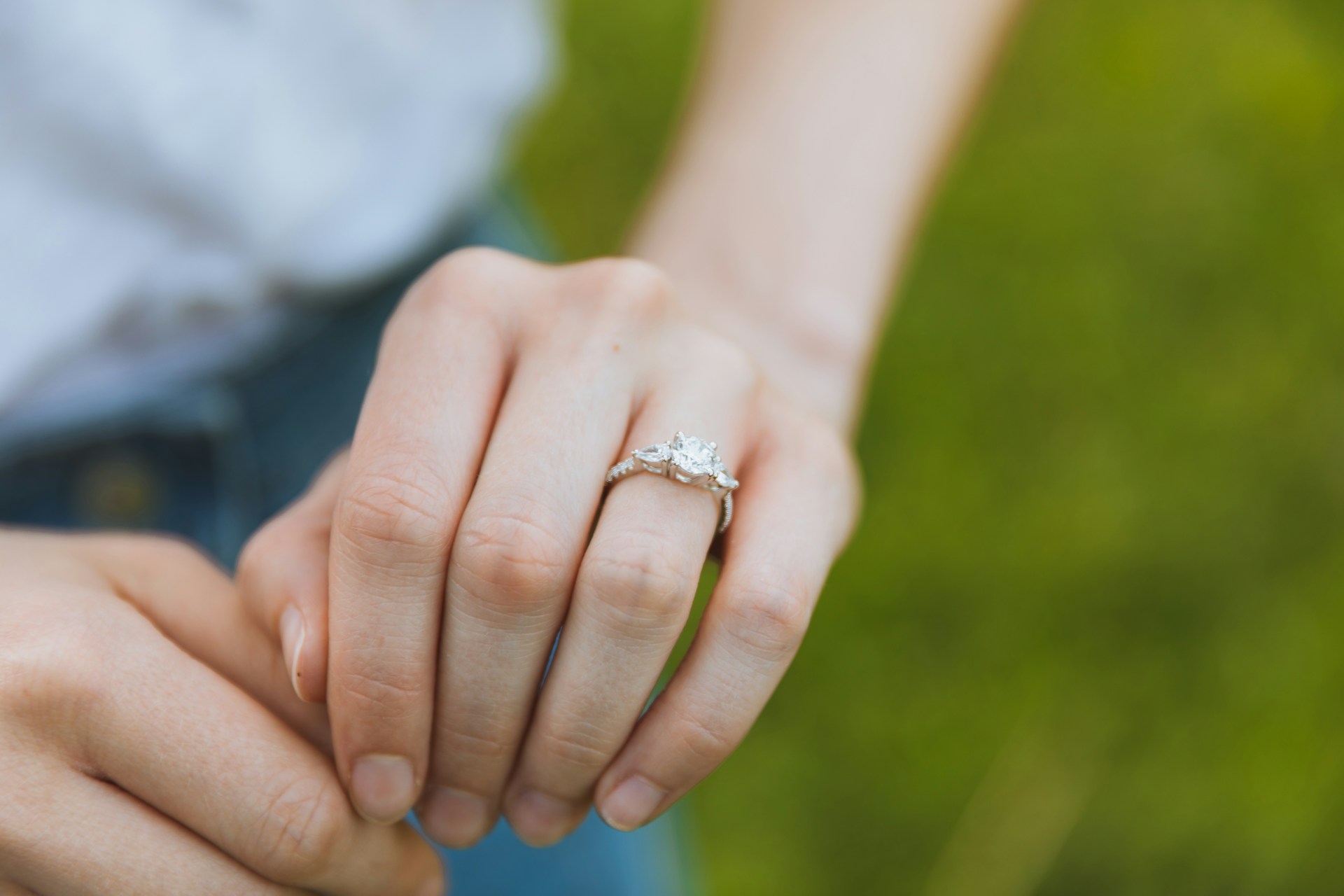 a woman’s hand extended and adorned with a three stone engagement ring