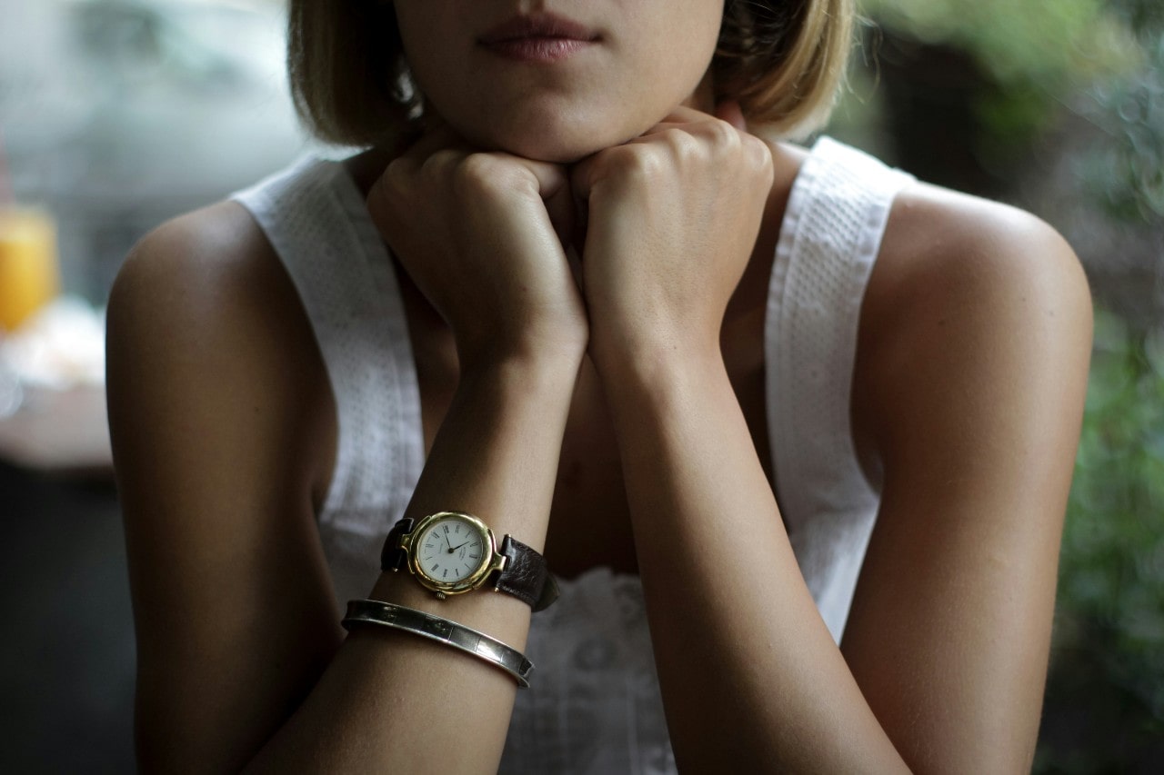 A close-up of a woman wearing a luxury watch with a leather strap.