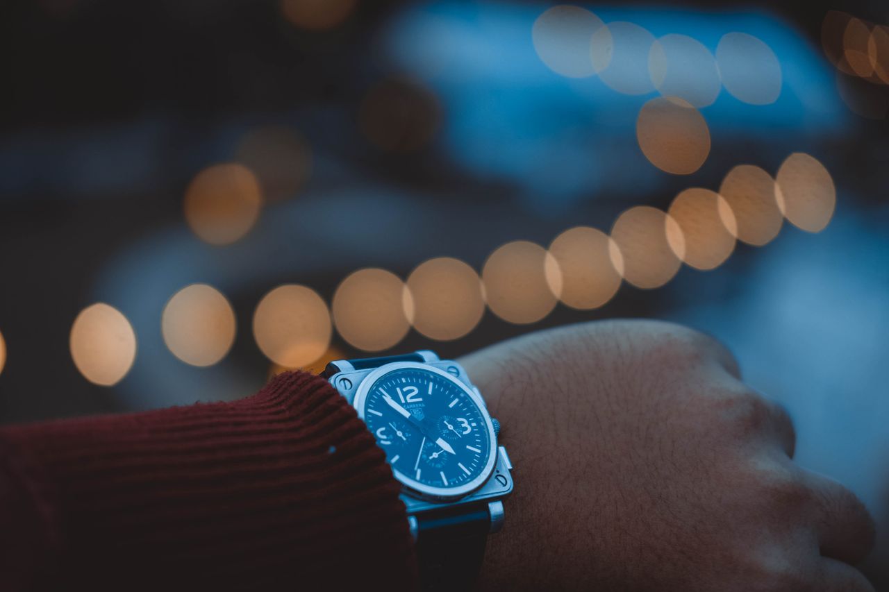 A close-up of a square watch face with a luminous dial.