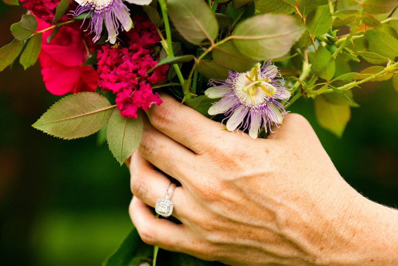 A woman holds a bouquet of flowers while wearing a halo ring.
