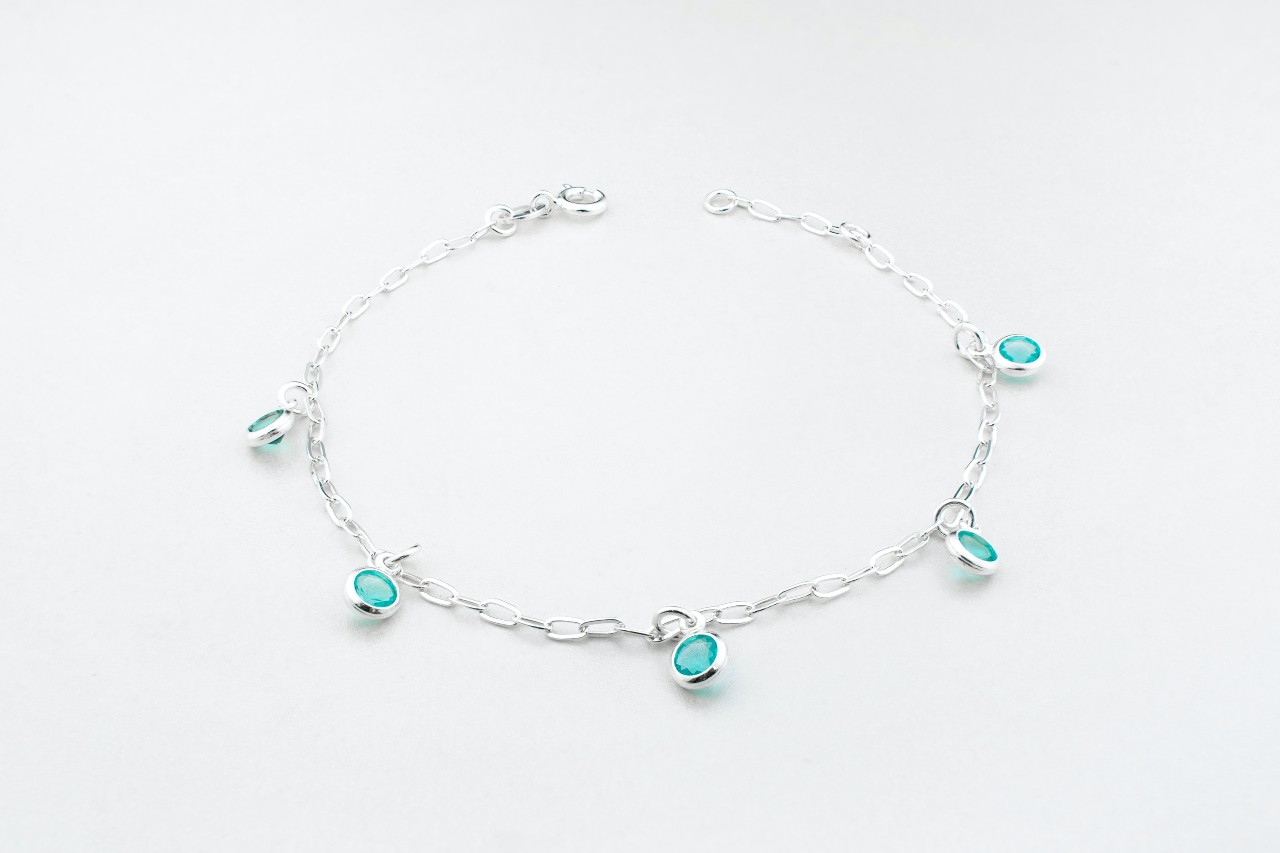 a white gold chain bracelet with bezel set blue gemstones