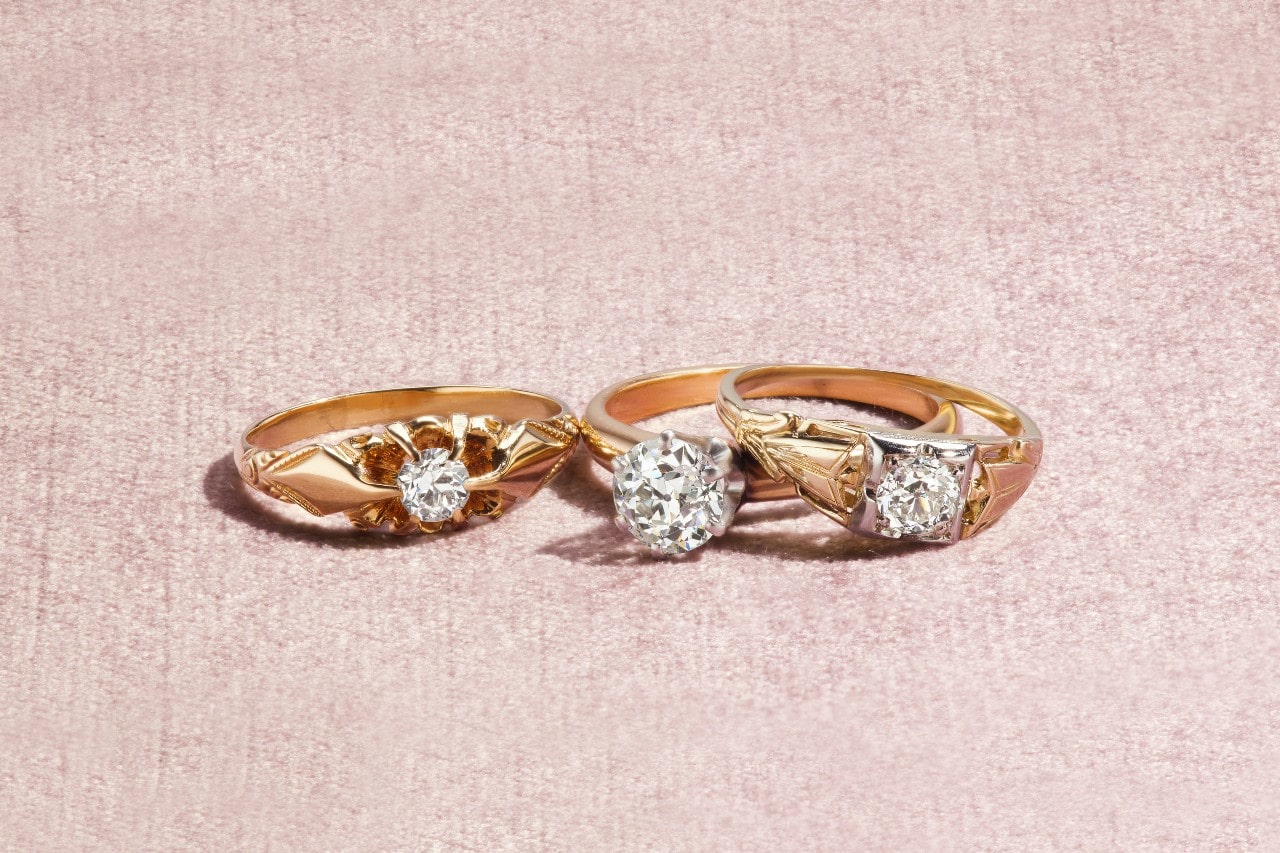 three yellow gold solitaire engagement rings with intricate designs